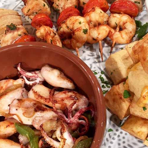 Calamaretes encebollados, papas bravas y brochette de pollo y langostinos