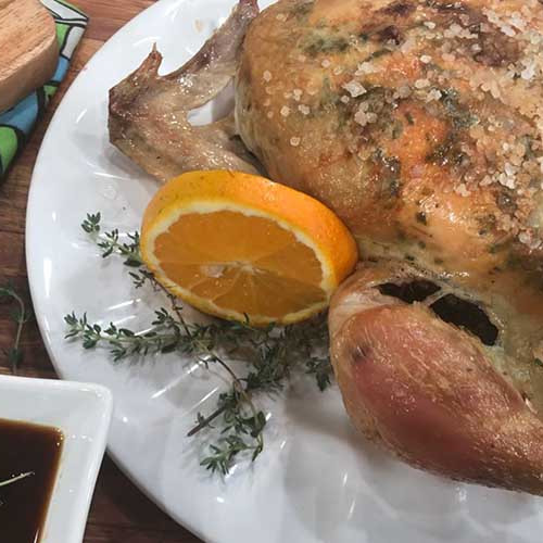 Pollo a la manteca de hierbas con salsa de naranjas y papas especiadas