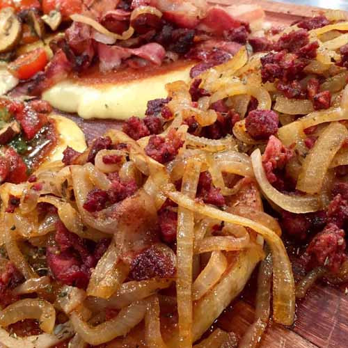 Provoleta cubierta de cebolla, panceta y chorizo colorado a la chapa