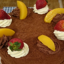 Torta de panadería con crema, duraznos y frutillas